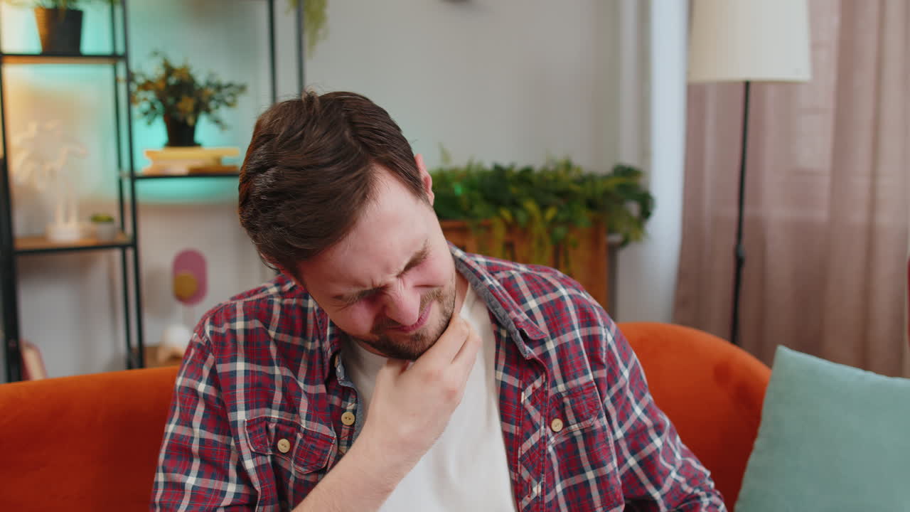 Upset man holds hands over sore throat painful neck frowning thyroid disorders tonsils inflammation