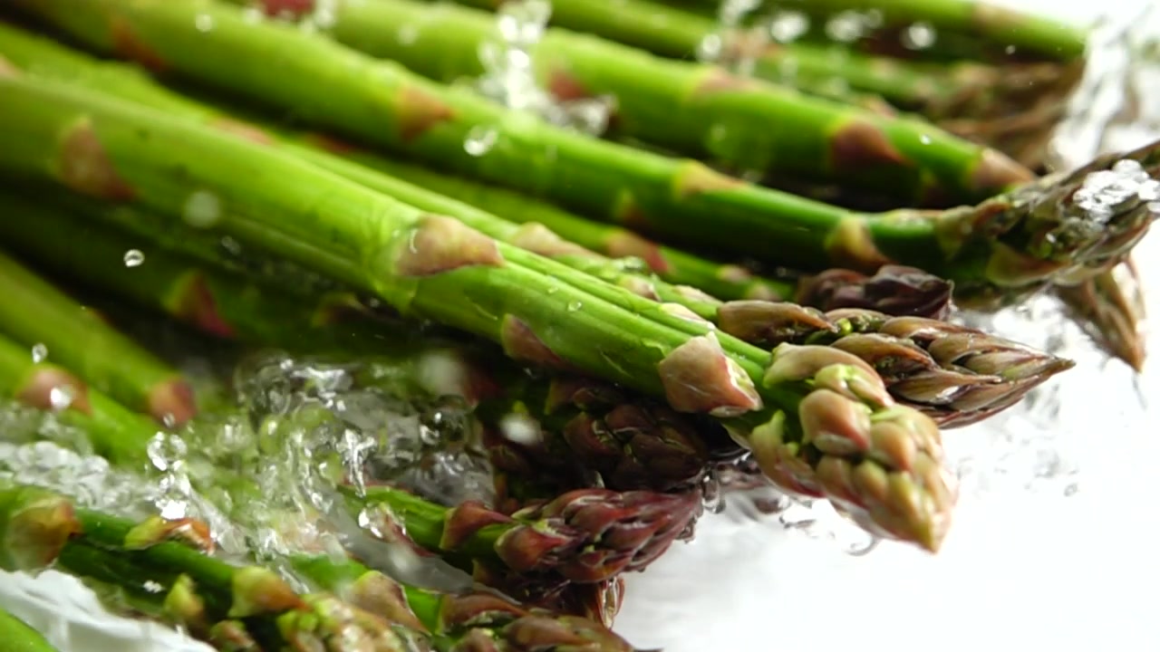 Fresh green asparagus. Water splashes. Slow motion.