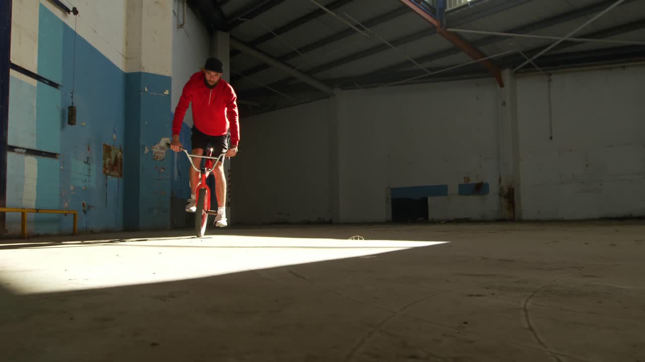Ciclista BMX in un magazzino vuoto.