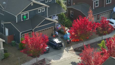 a suburban american home with a yard full of inflatables surrounded by red leaves in the trees