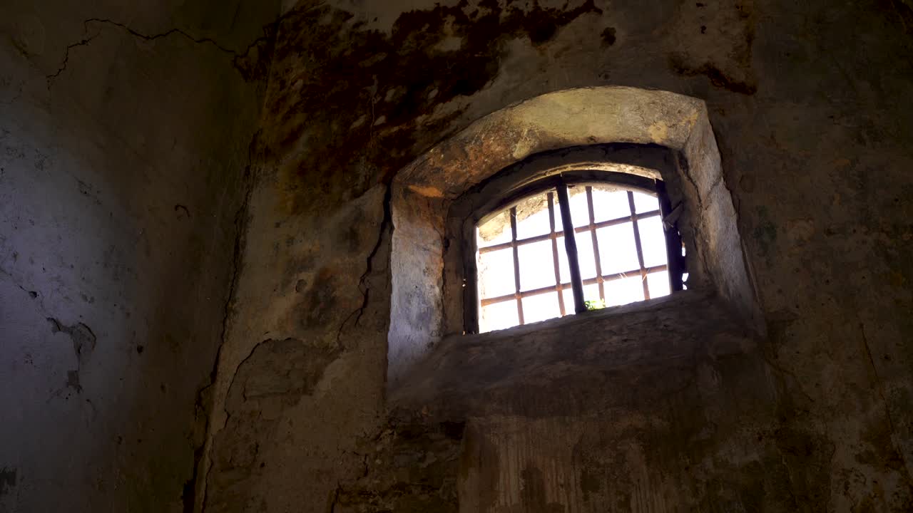 ventana de mazmorra con hierros y paredes sucias arruinadas dentro de la fortaleza medieval, lugar histórico