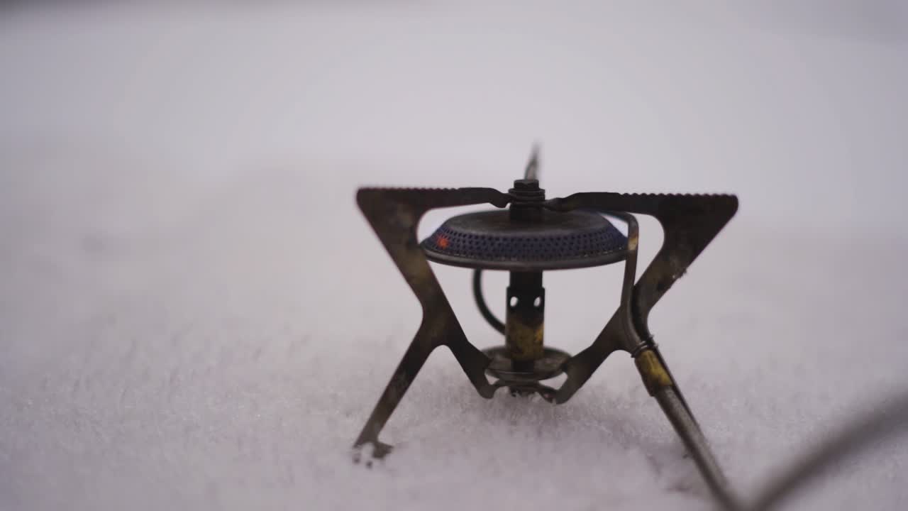 Fire starting on a gas stove in the snow. Hiking adventure. Preparing hot drink outdoors.