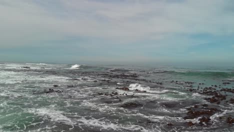 Drone-flying-low-over-open-rough-seas-with-bamboo-floating-on-the-surface-as-swells-and-waves-come-in-and-break