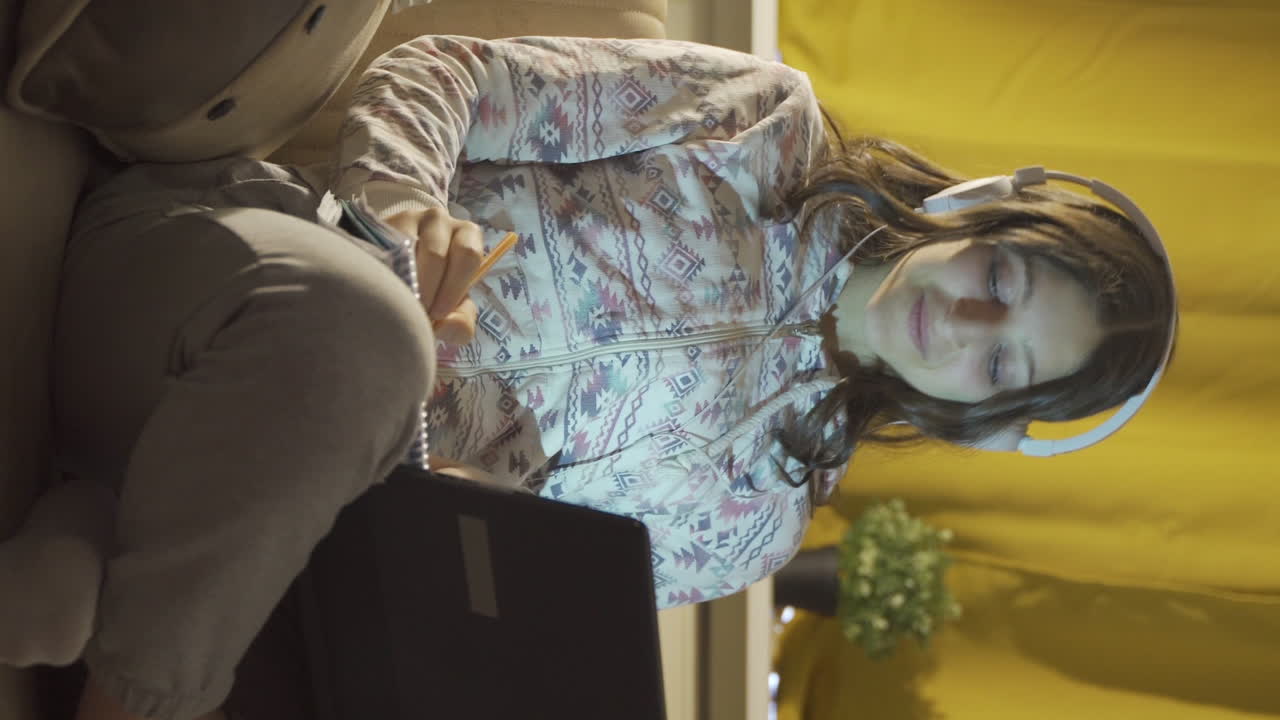 video vertical de un estudiante masculino escuchando música y estudiando por la noche.