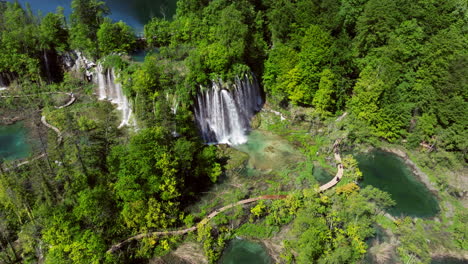 waterfalls and path in plitvice lakes national park on a sunny day in croatia. - aerial shot