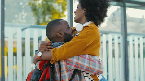 Happy-african-american-young-couple-meeting-at-train-station-and-hugging-on-nice-summer-day