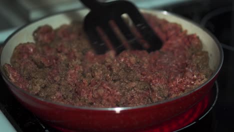 ground beef being moved around with spatula in red pan