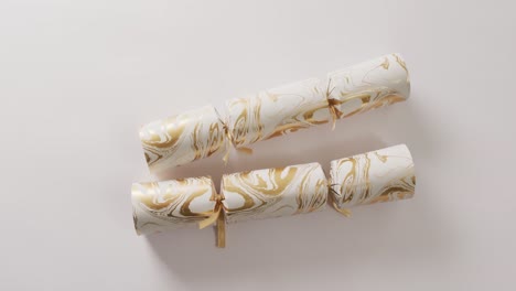 video of two white and gold christmas crackers and copy space on white background