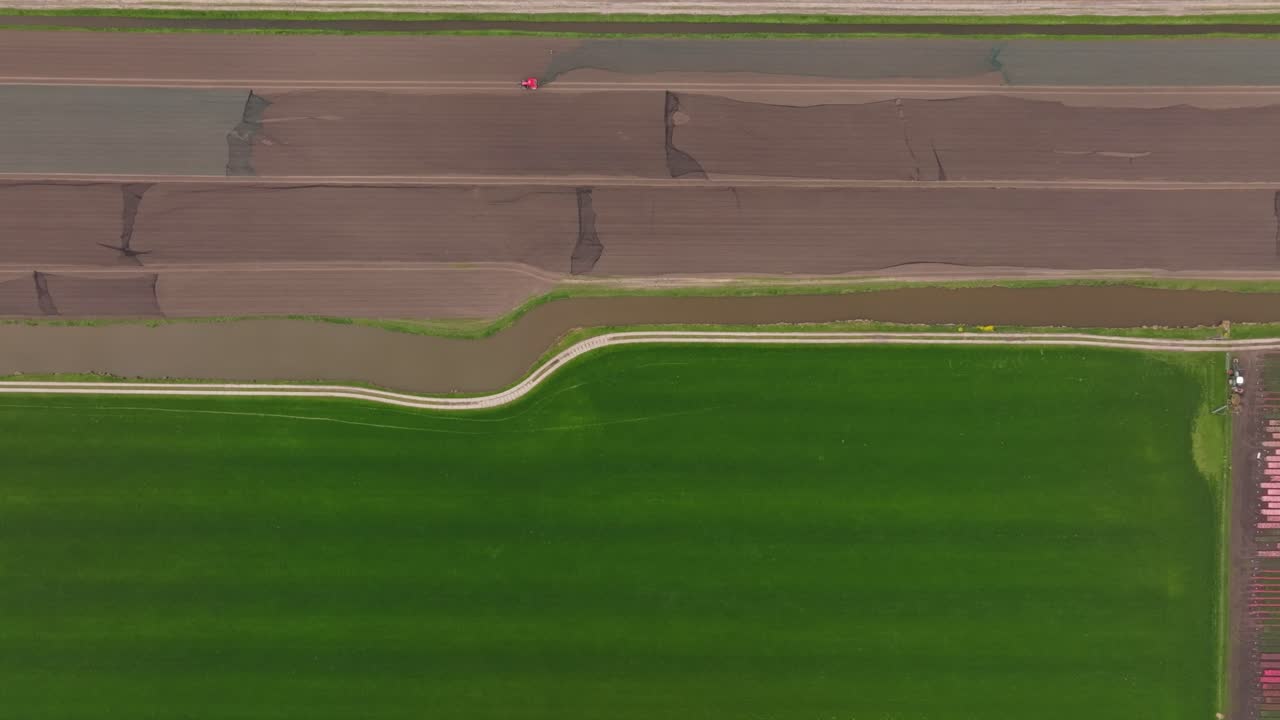 Aerial view of tractor plowing wet farmland in rural Netherlands