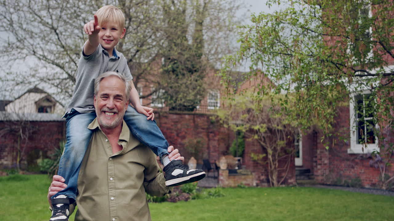 Grandfather carrying his grandson on his shoulders in the garden