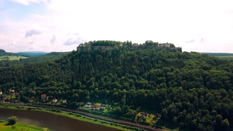 Drone-rising-up-to-film-an-ancient-castle-in-the-center-of-Europe-with-green-forests-and-trees-and-bright-skies