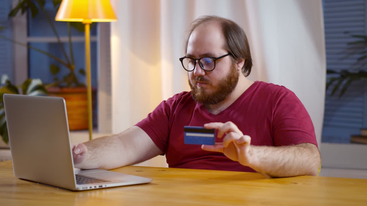 Giovane uomo che usa la carta di credito per pagamenti di acquisti online sul laptop