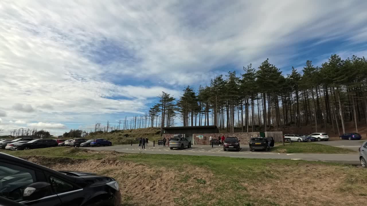Time lapse busy Newborough forest car park tourists arriving at scenic Welsh coastal woodland beach