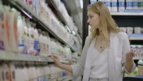 woman choosing and buying fresh organic dairy products at grocery store