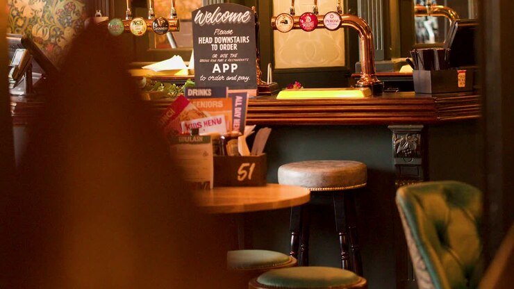 Interno di un pub vintage illuminato, tavoli vuoti, lenta panoramica della telecamera, atmosfera invitante, arredamento classico