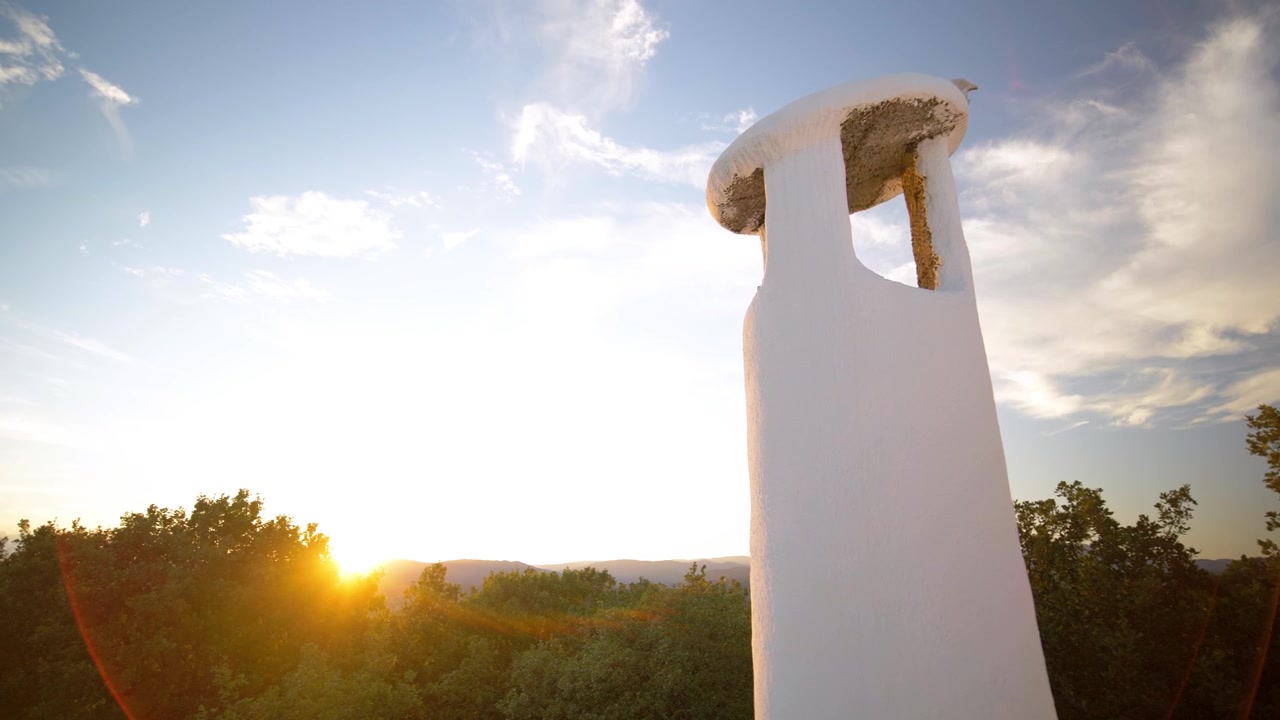 Un tramonto sereno: la perfetta combinazione di cielo blu, alberi verdi e un camino bianco, che crea un bellissimo paesaggio naturale per relax e ispirazione.