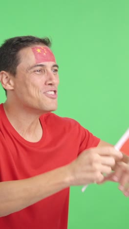 man cheering for china waving a national flag looking away