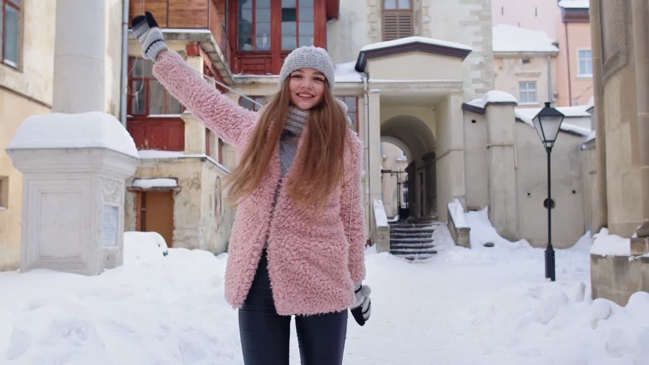 매력적인 젊은 소녀 관광객이 춤을 추고, 축하하고, 오래된 도시 중심부에서 휴가를 보내는 동안 미소 짓고 있습니다.
