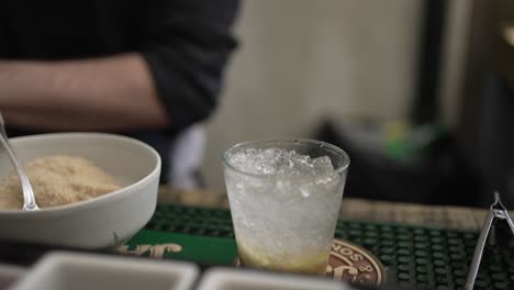 bartender pouring a drink into a glass filled with ice at a bar