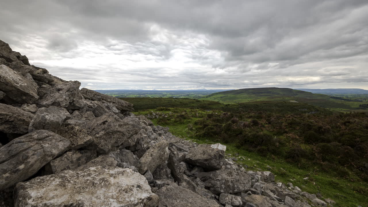 Time-lapse af landligt og fjerntliggende landskab med græs, træer og klipper om dagen i Carrowkeels bakker i Sligo Amt, Irland