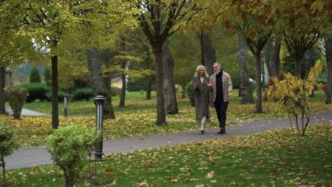 happy elderly couple walking along path in elegant outerwear