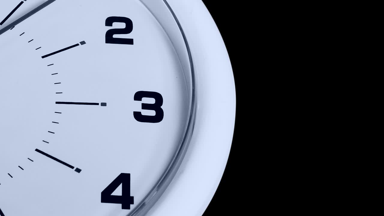 Video footage of a wall clock numbers and a ticking arrow, shot with dark background