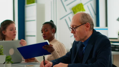 elderly businessman looking at camera smiling sitting in brainstorming room