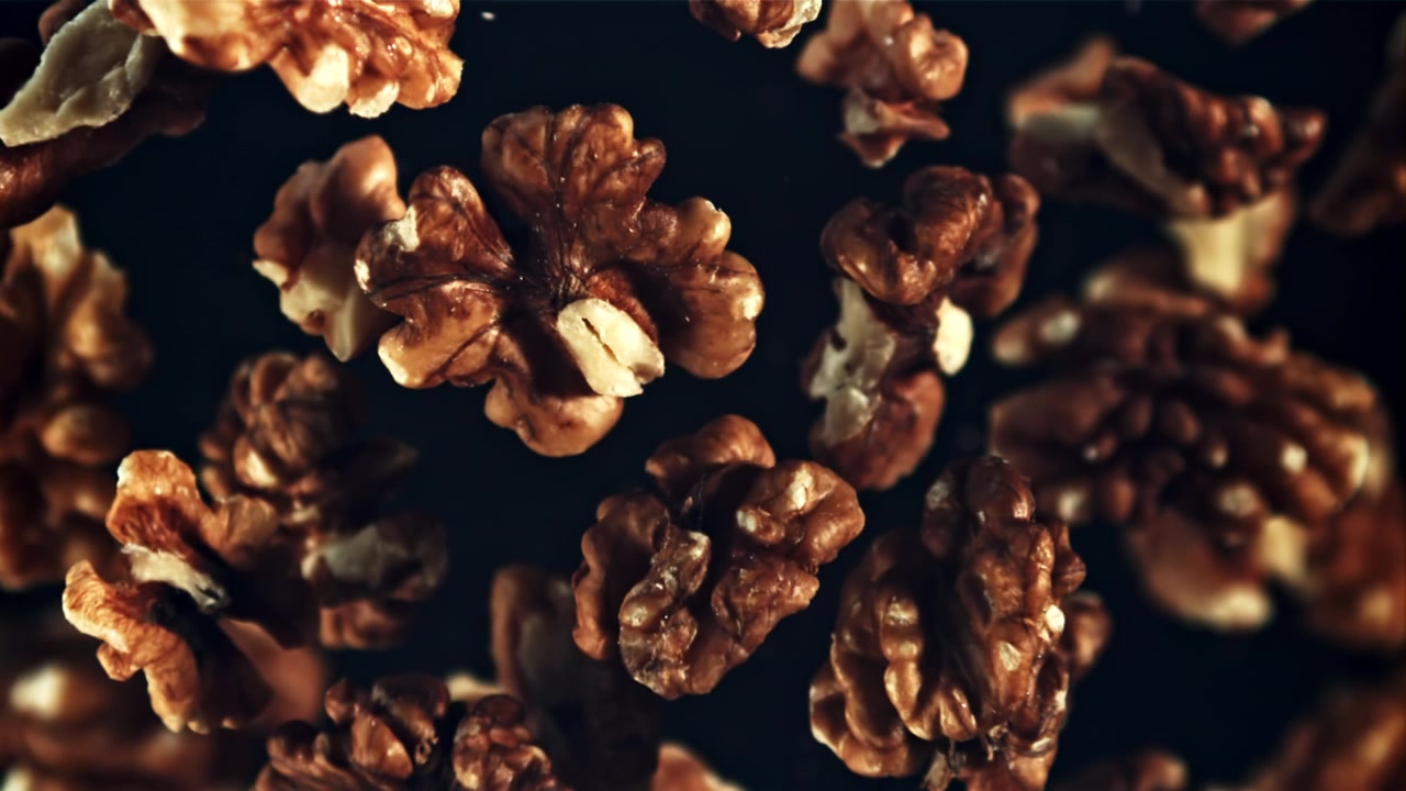 Peeled Walnuts Falling in Slow Motion Against a Dark Background