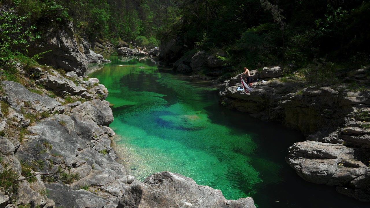 Persone che riposano su una roccia calcarea sopra la pozza fluviale turchese delle Pozze Smeraldine. Torrente Meduna, Italia
