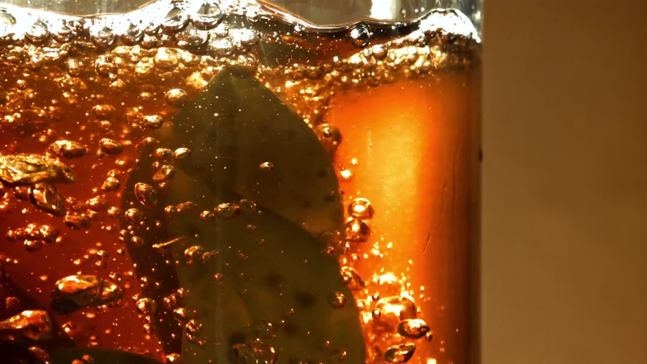 Bidikan Makro Daun Teh Meresap dalam Minuman yang Menggelembung
