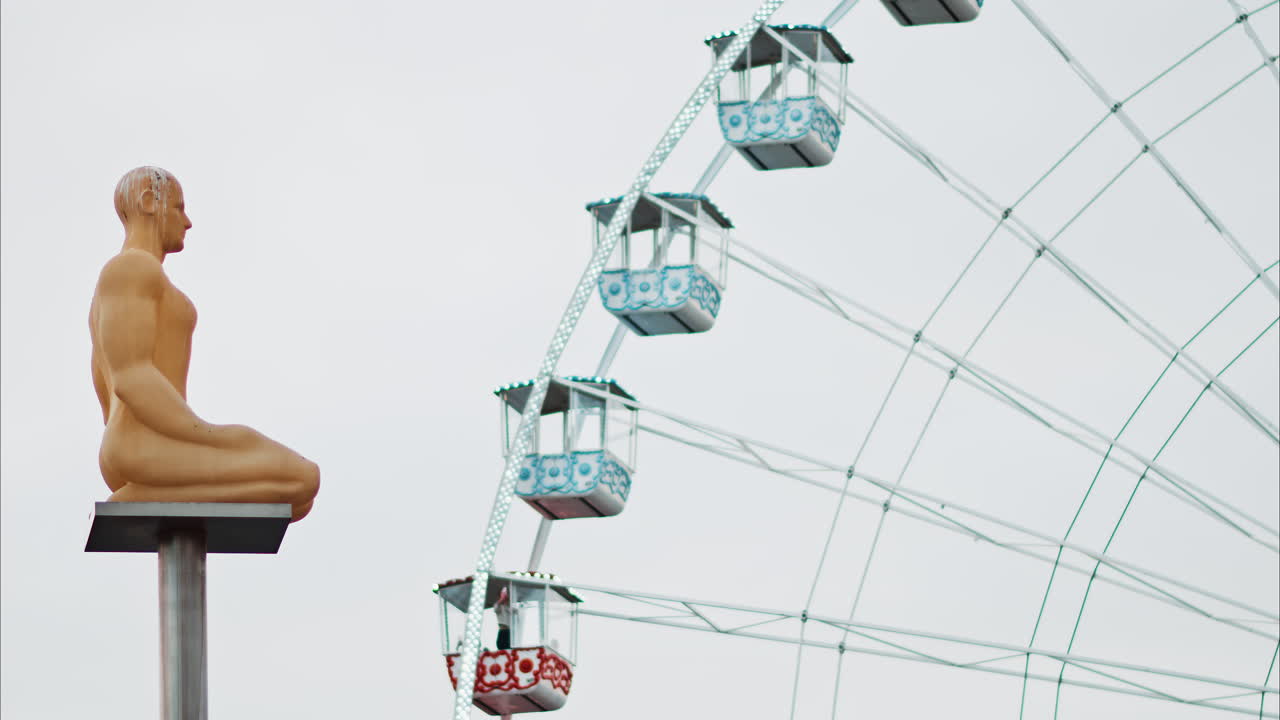 Nice, France - December 8, 2024: Conversation a Nice statue by Jaume Plensa at Place Massena with a ferris wheel on the background