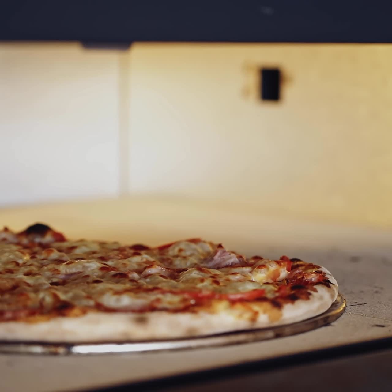 Pizza is getting ready in oven. Chef opening oven door and checking pizza readiness. Cook checks pizza for readiness using the pizza ring.