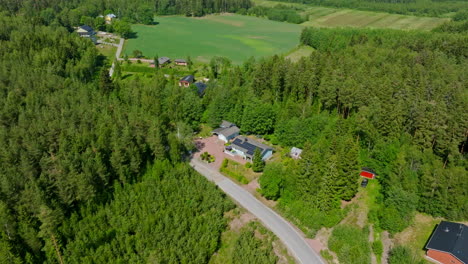 Establishing-drone-shot-of-a-sustainable-house-in-middle-of-forest-and-rural-fields