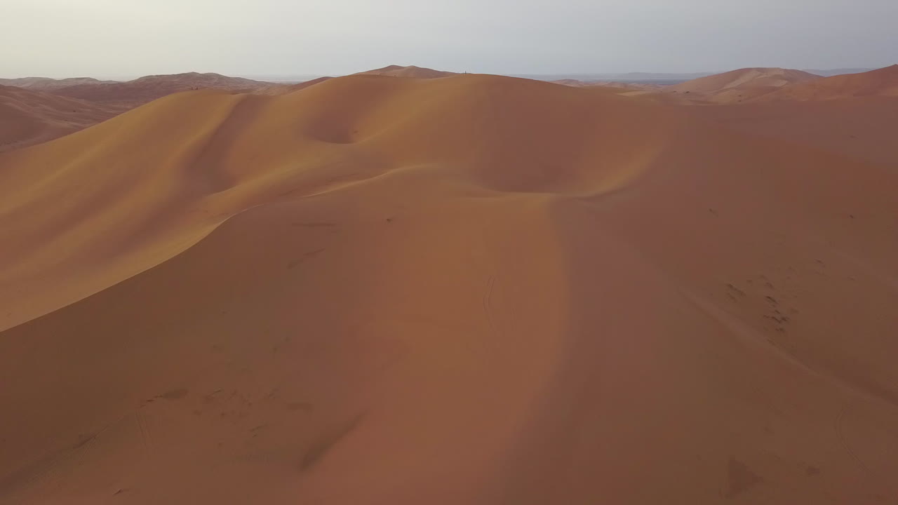 Ripresa con drone che si allontana lentamente sui mari di dune di sabbia del Marocco.