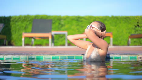 Eine-Junge-Frau,-Die-Noch-Nass-Vom-Schwimmen-Ist,-Glättet-Ihr-Haar,-Indem-Sie-Die-Hände-Vom-Gesicht-Wegzieht