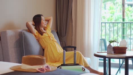 young woman traveler sitting and relaxing in a hotel room while on summer vacation, travel lifestyle concept