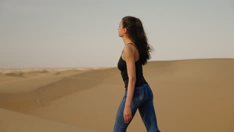 una mujer caminando en el desierto de gobi, una brisa ligera soplando su cabello.