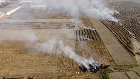 Tiro-De-Inclinación-Aérea-De-Rastrojo-En-Llamas-En-Un-Vasto-Campo-Abierto