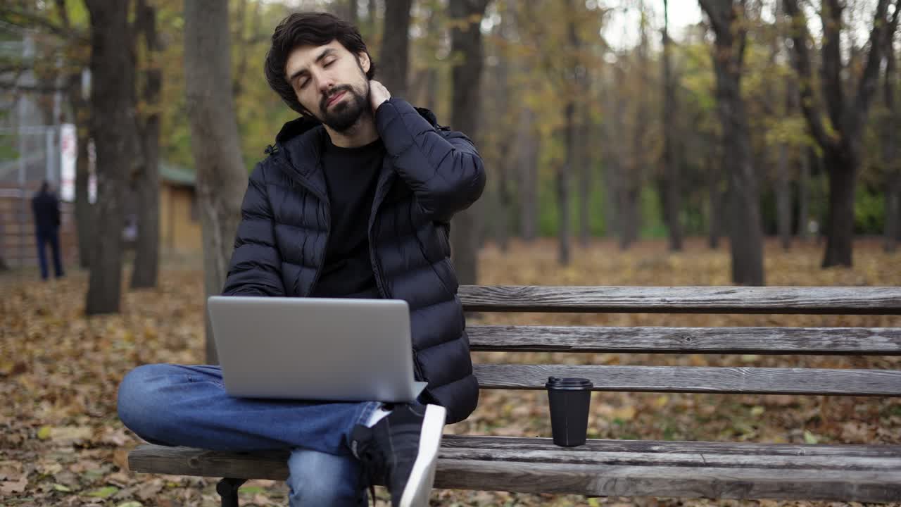 Freelance che lavora con un laptop nel parco da sola, si sente stanca