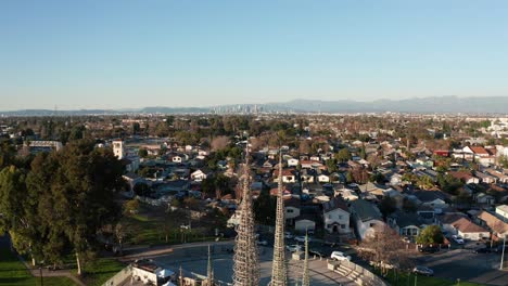 reverse pullback aerial shot of the watts towers with downtown los angeles in the distance