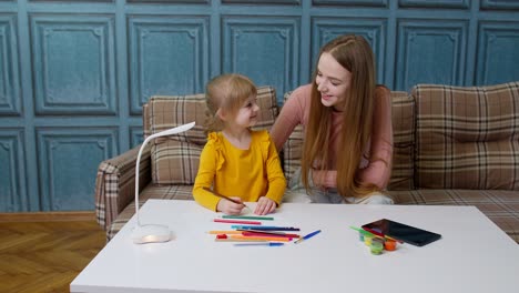 mujer y niña sonriendo mientras dibujan juntos en un sofá