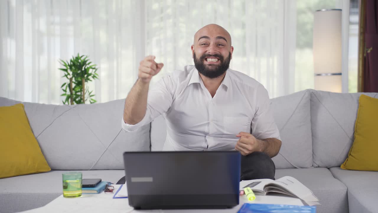 Home office worker man experiencing joy looking at camera.