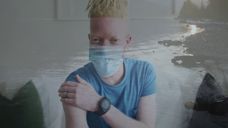 Wearing mask and blue shirt, person with ocean waves animation overlaying scene
