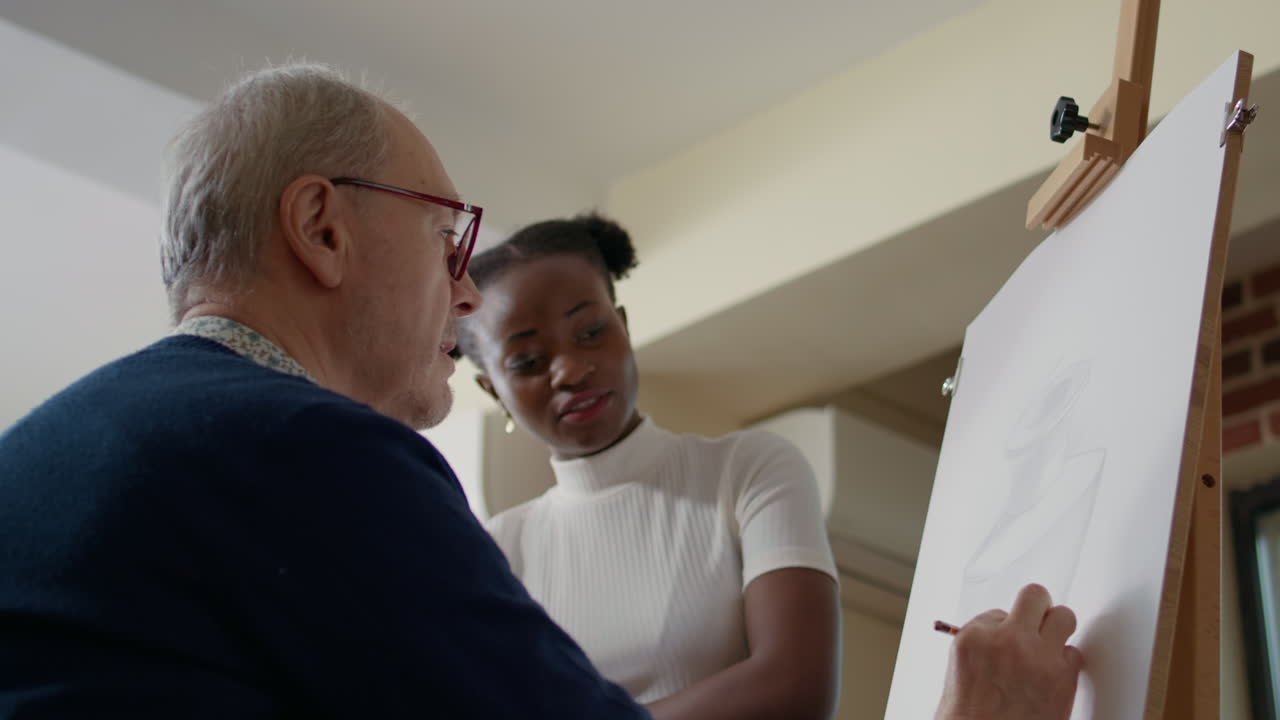 Senior man attending drawing lesson with teacher in art class