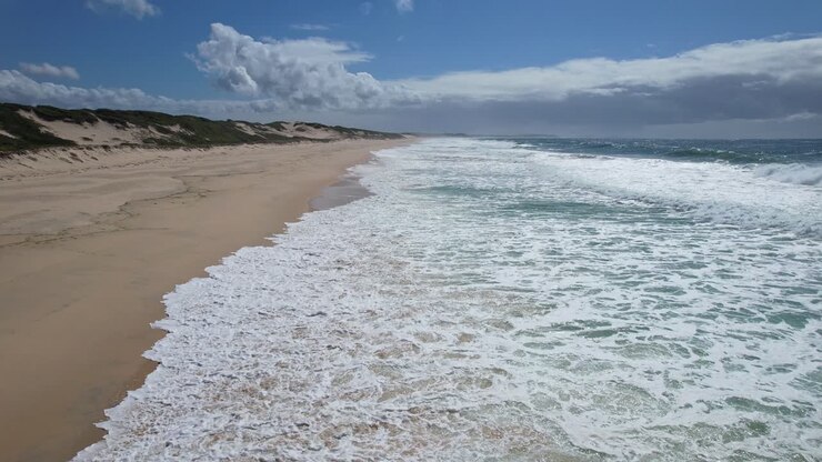 Weiße, schaumige Wellen rollen über Sanddünen am Mungo Beach, New South Wales, Australien