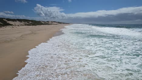 witte schuimige golven rollen over zandduinen in mungo beach, new south wales, australië