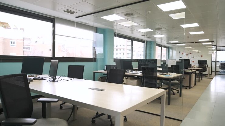 Interior de oficina espaciosa con ordenadores en las mesas.