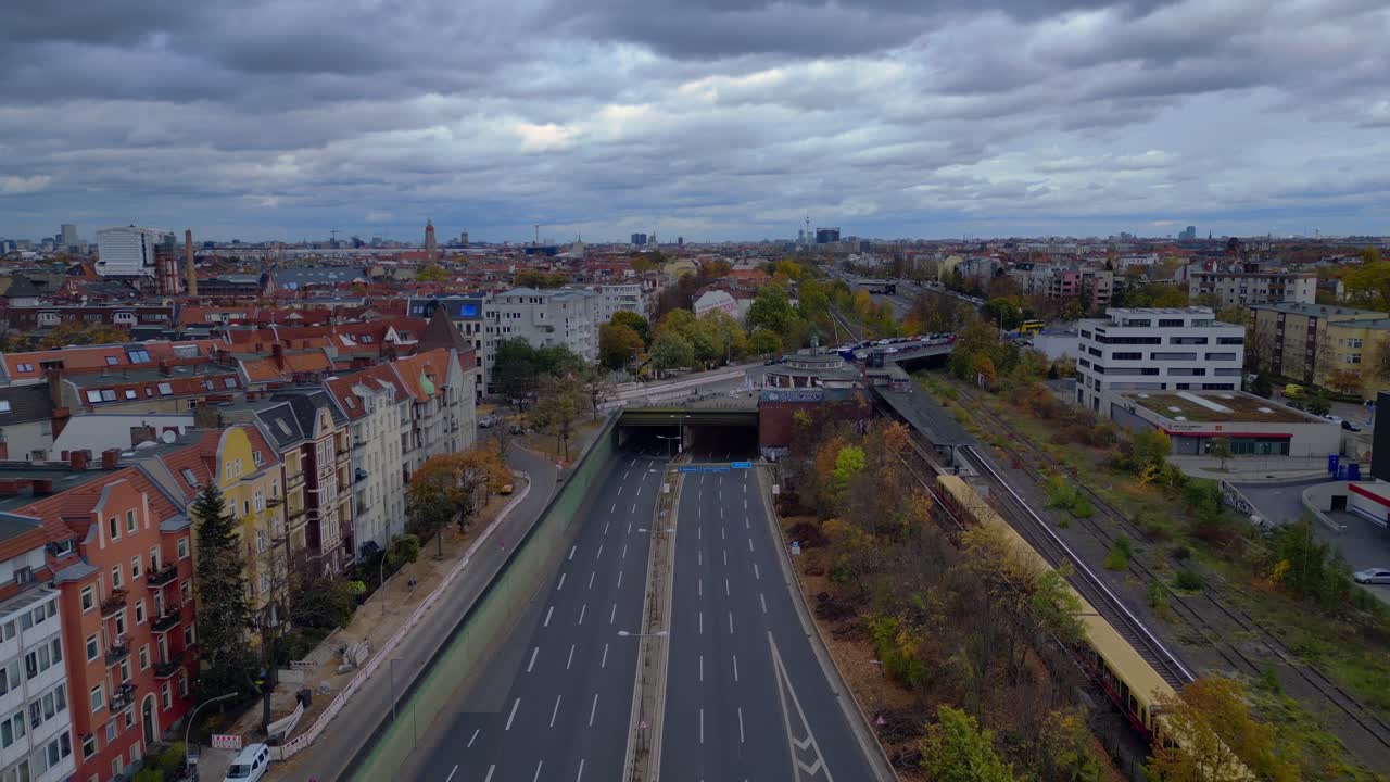 Urban landscape showing a major highway system and yellow S Train in Berlin Steglitz with dramatic clouds. Magic aerial view flight fly reverse drone