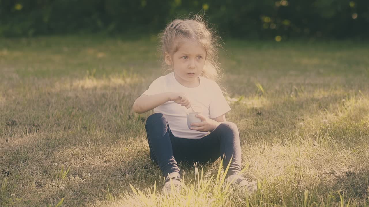 chica con cabello rubio y ojos grandes come delicioso yogur