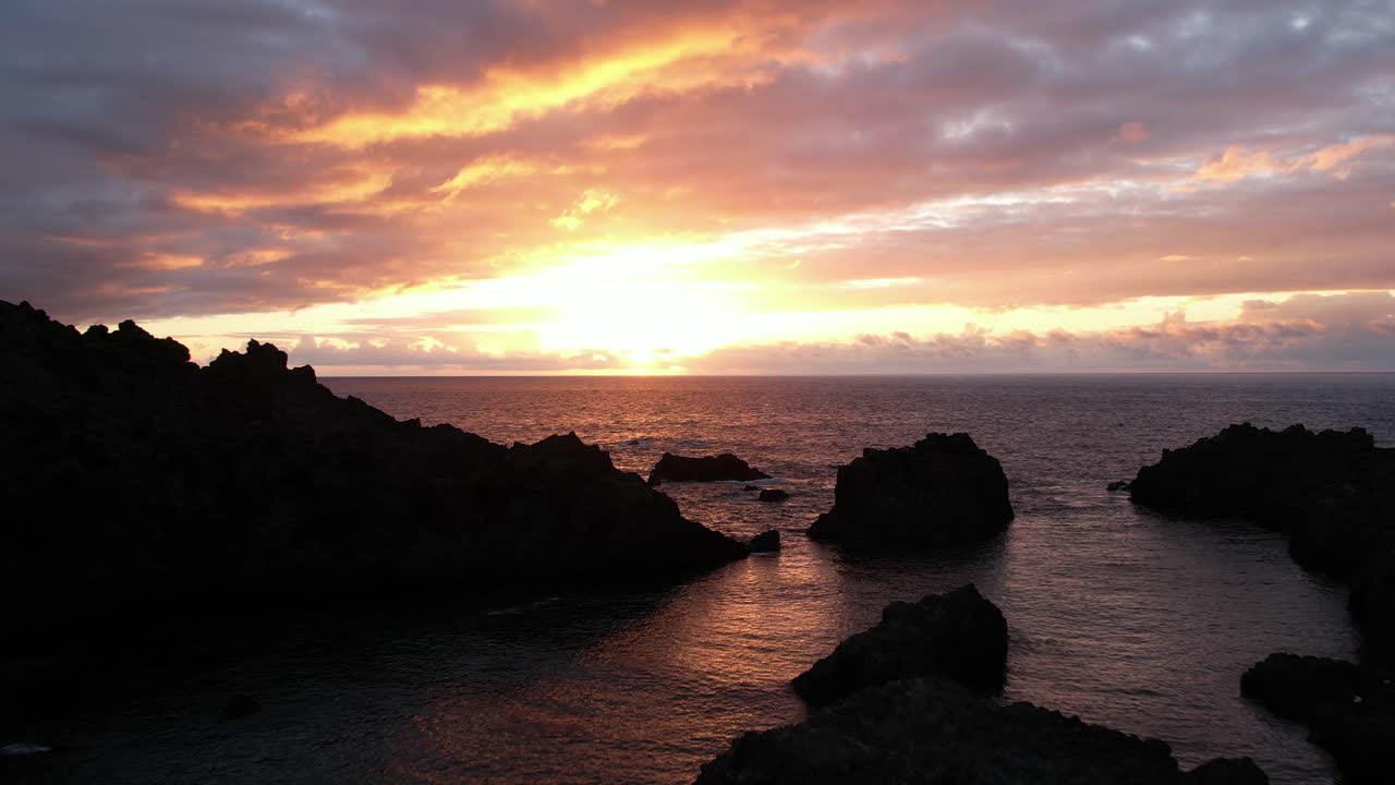 Rocks and waving sea against sundown sky